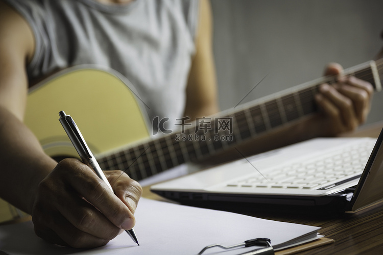 作曲家拿着铅笔在纸上写歌词。