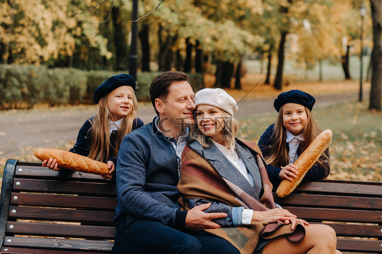 一个大家庭坐在秋天公园的长凳上