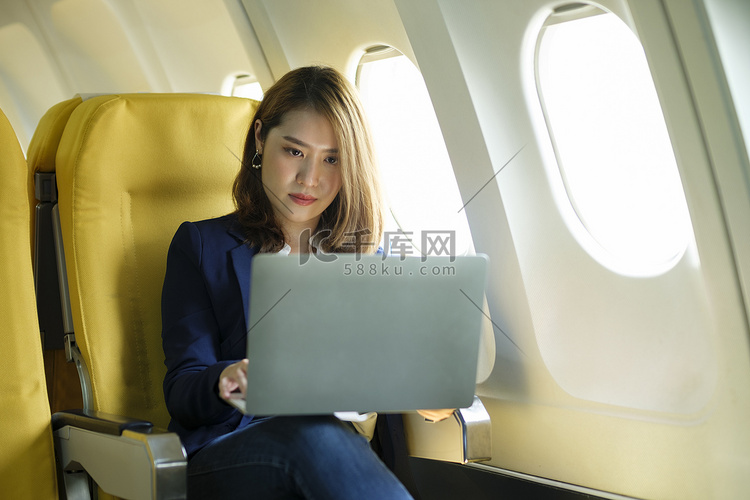 女商人在飞机上，使用笔记本电脑