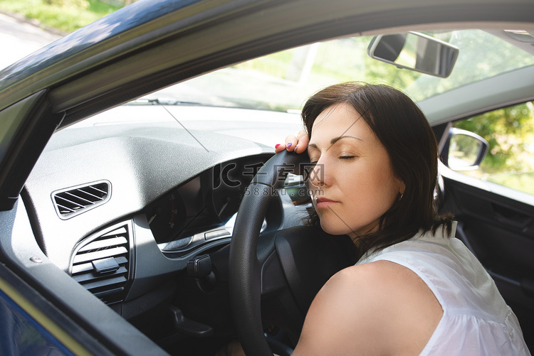 疲惫的女人在车的方向盘上睡着了