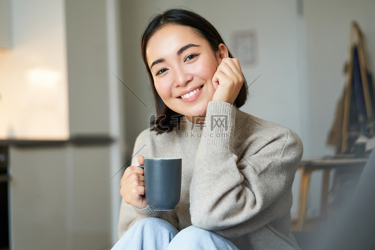 微笑的亚洲女性坐在家里喝咖啡，