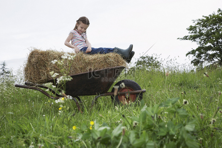 女孩（5-6）坐在田间独轮车的