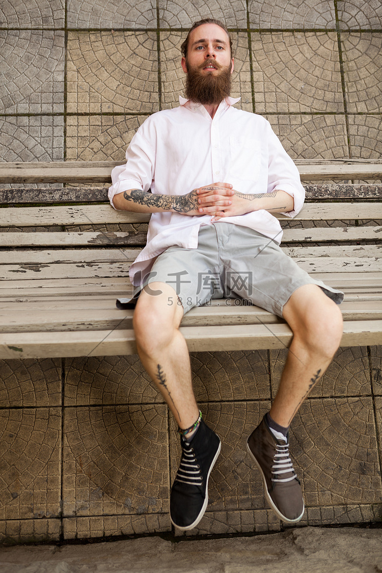 留着胡子的纹身嬉皮士躺在长凳上