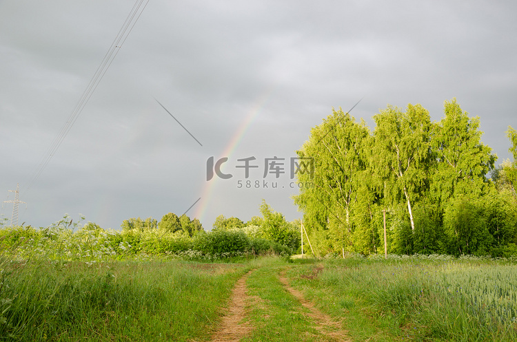 雨后彩虹在绿树和乡村小路上