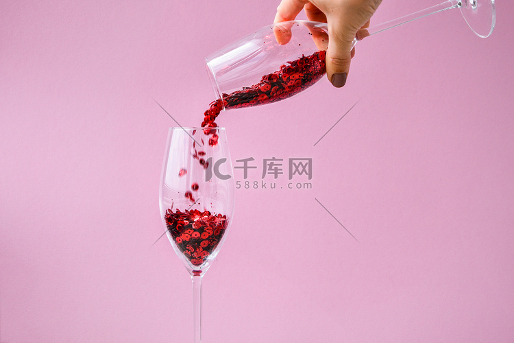 红色纸屑落入粉红色背景的香槟杯
