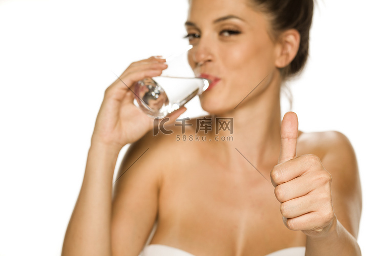 年轻美女从玻璃杯里喝水