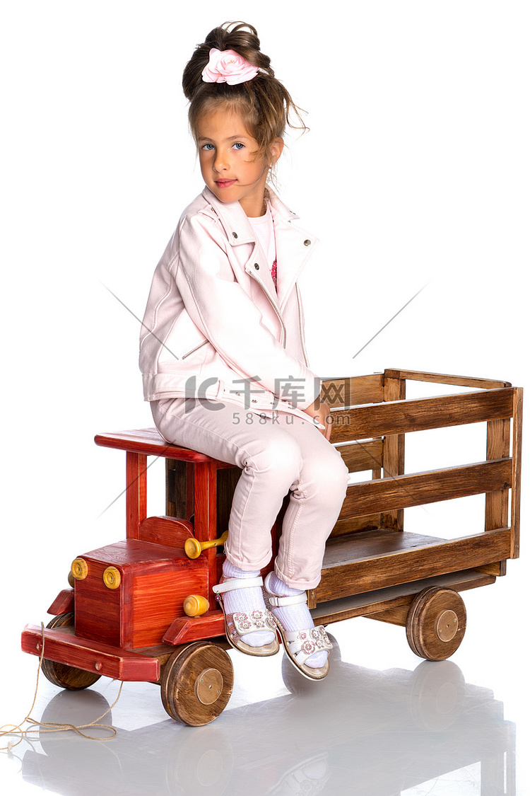 小女孩正在玩一辆木制汽车。
