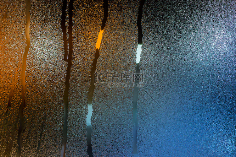 夜间湿窗玻璃的抽象背景，带有青