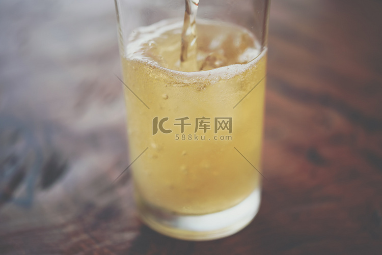 将啤酒水倒入装有冰块和泡沫的玻