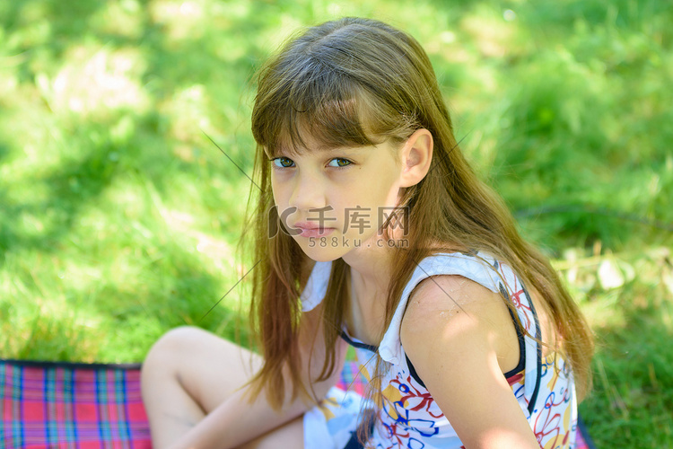 一个悲伤的小女孩在绿色公园野餐