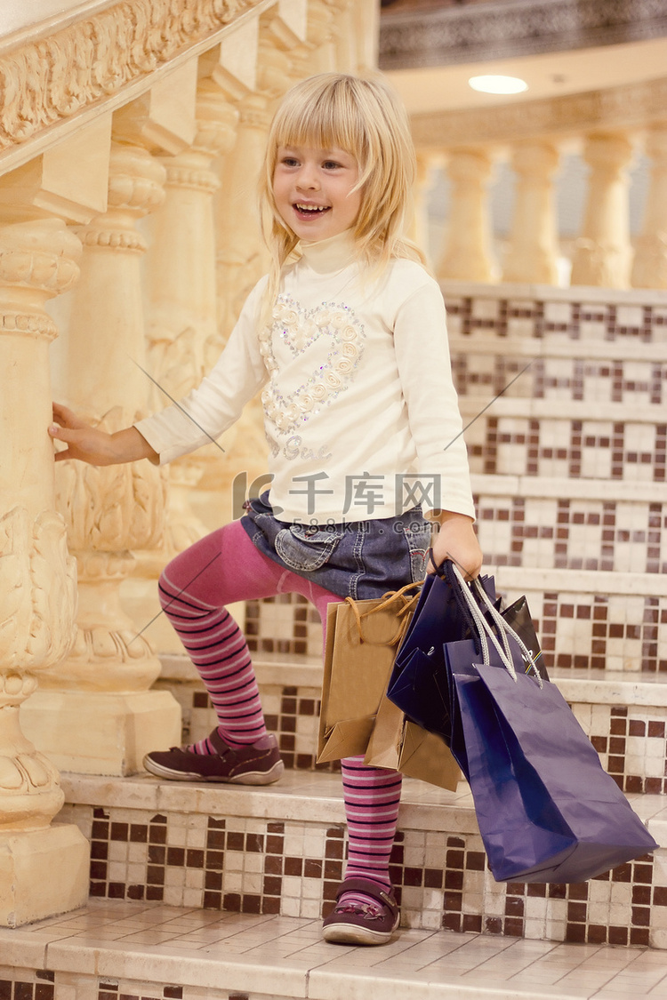 3 岁的金发女孩站着购物