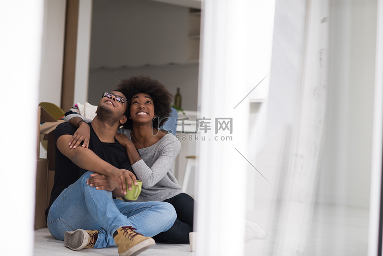 放松在新房的非裔美国人的夫妇