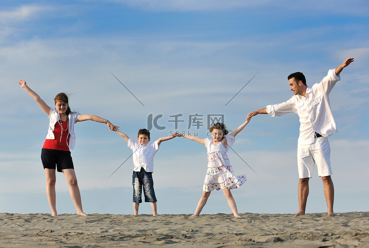 快乐的年轻家庭在海滩上玩得开心