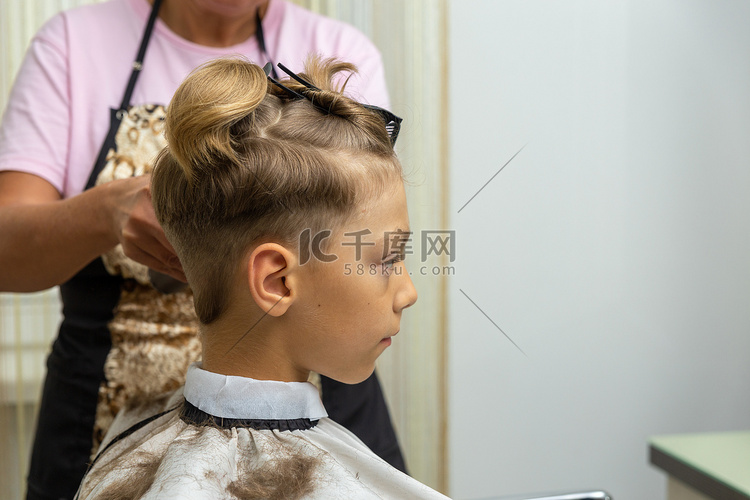 漂亮的欧洲男孩在理发店做发型。