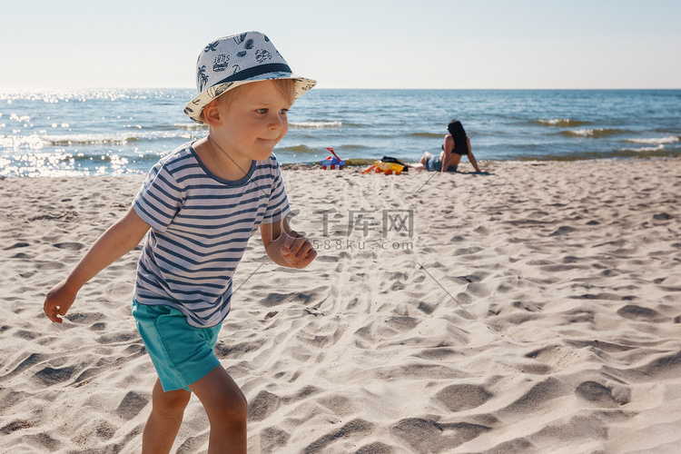 可爱的小男孩在孤独的海滩上玩得