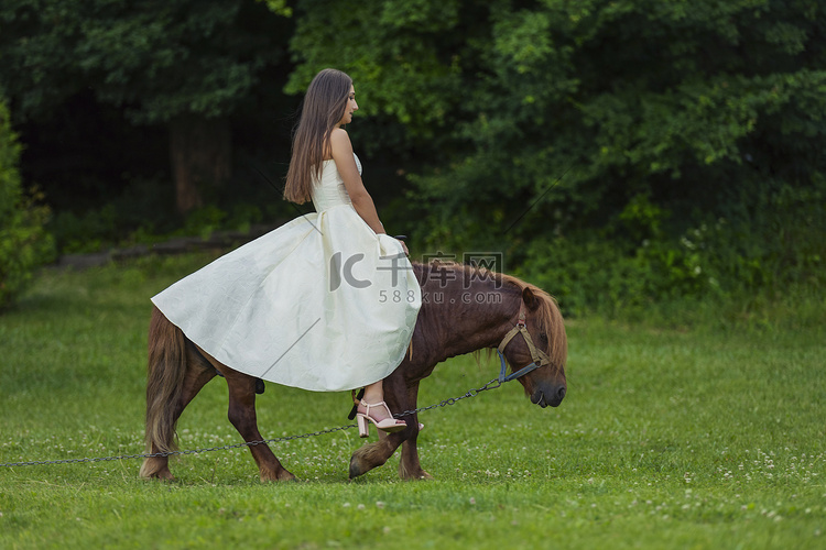 穿着白色连衣裙的女孩骑着小马