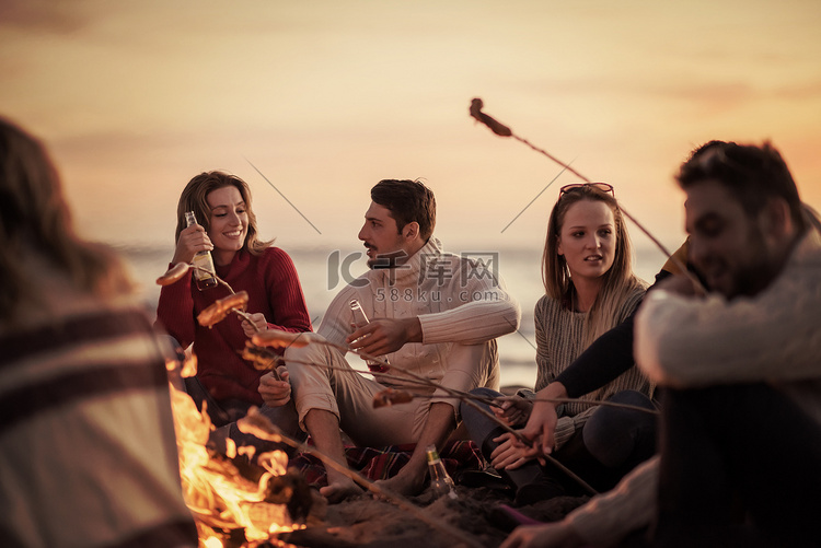 一群年轻的朋友坐在海滩的火边