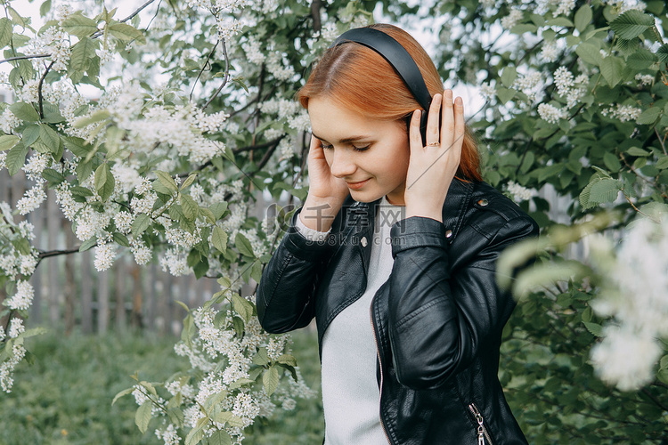 一名红发少女戴着耳机听音乐，耳