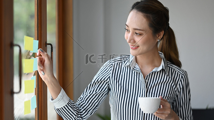微笑的女领导喝着咖啡，指着玻璃