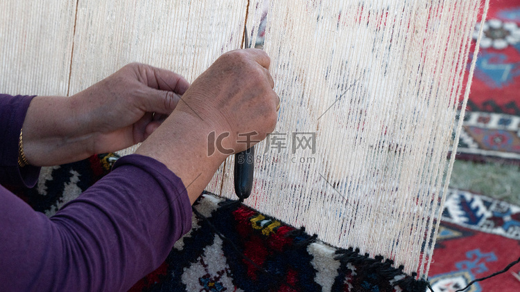 女手在织机、纺织工业上编织地毯