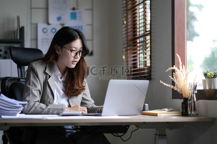 美丽的亚洲女商人坐在办公室的笔