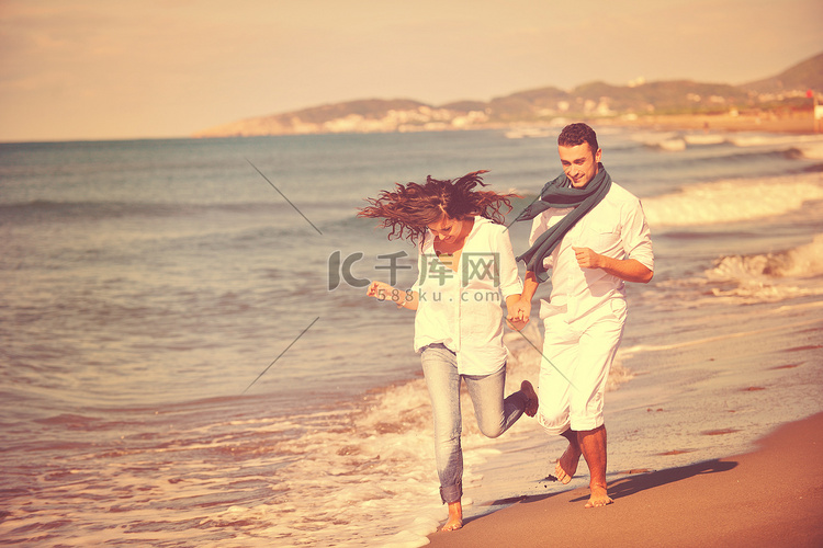 快乐的年轻夫妇在美丽的海滩玩得