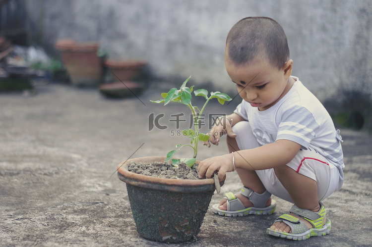 有花盆的可爱小男婴喜欢在泥土中