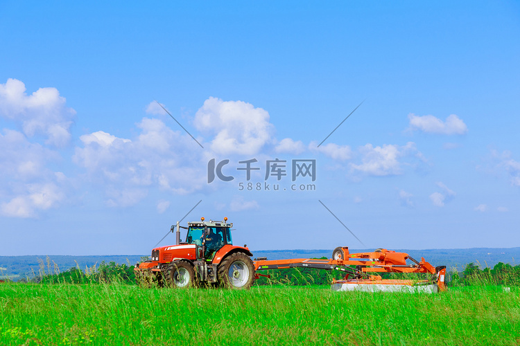 割草机连接到拖拉机在田间行驶，