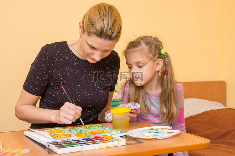女艺术家教一个小女孩在桌子上在