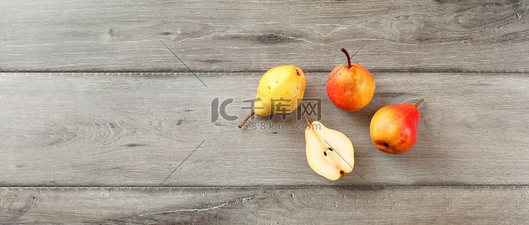 四个成熟的梨，一个切成两半，桌