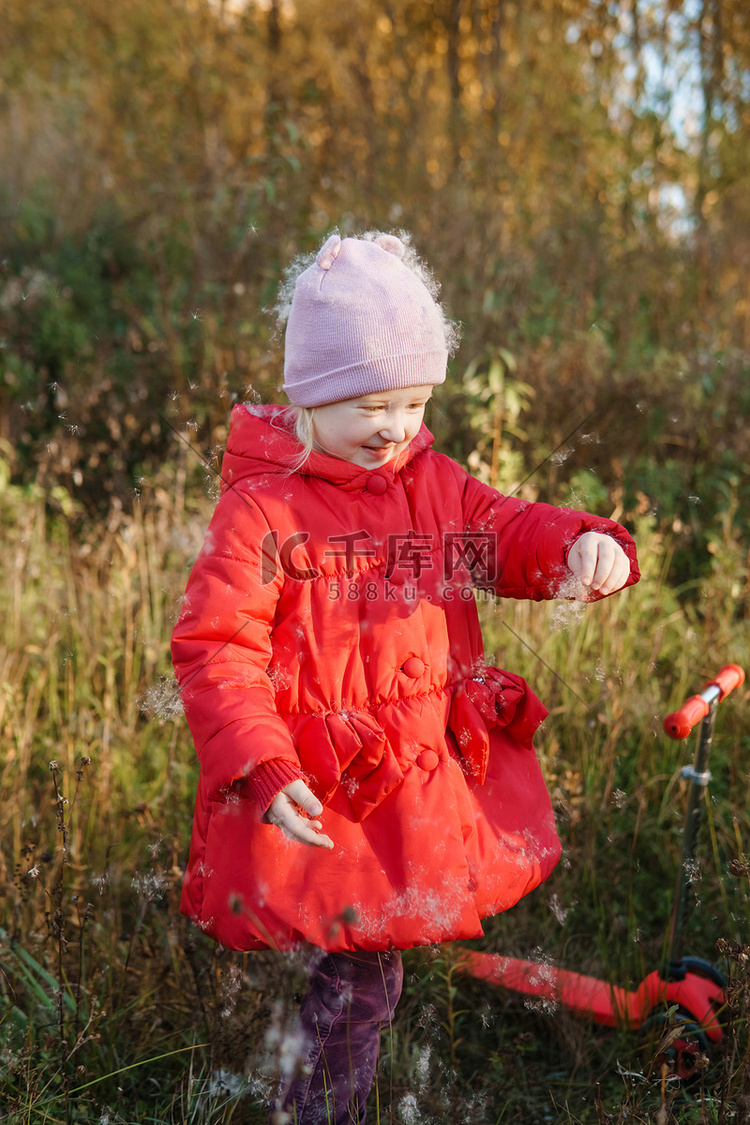 一个穿着红色外套的小女孩在秋天