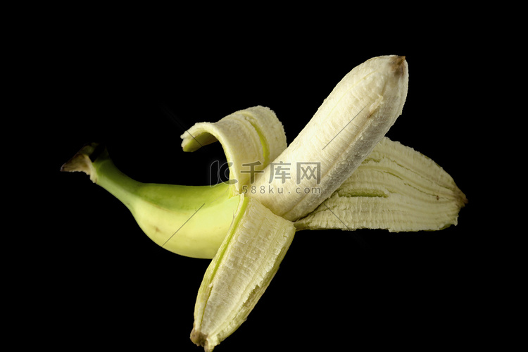 一根成熟的香蕉，半剥皮，黑色背