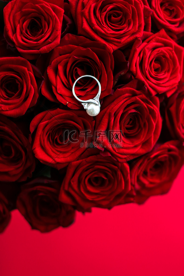 美丽的白金珍珠戒指和红玫瑰花束