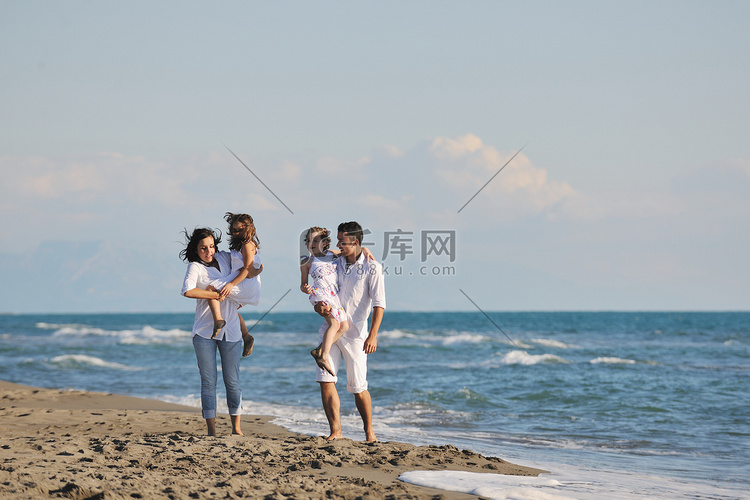 快乐的年轻家庭在海滩上玩得开心