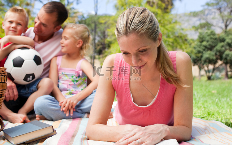 母亲和家人在野餐时专心读书