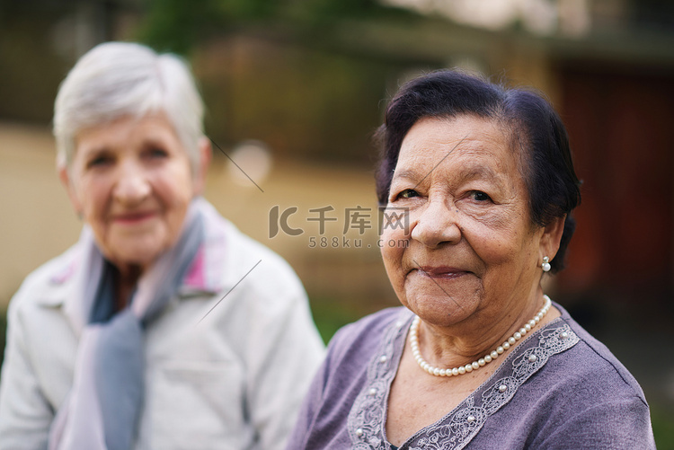 两位老年妇女坐在公园的长凳上，