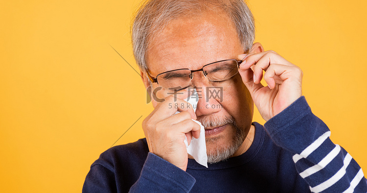 亚洲老人哭着举起眼镜用纸巾擦红