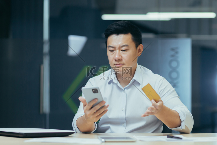 年轻的亚洲男性商人使用电话并进