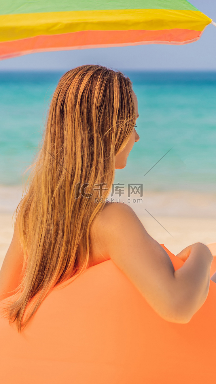 热带岛屿海滩上坐在橙色充气沙发