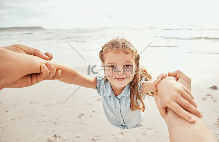 妈妈挽着小女孩的手臂在海滩上摇