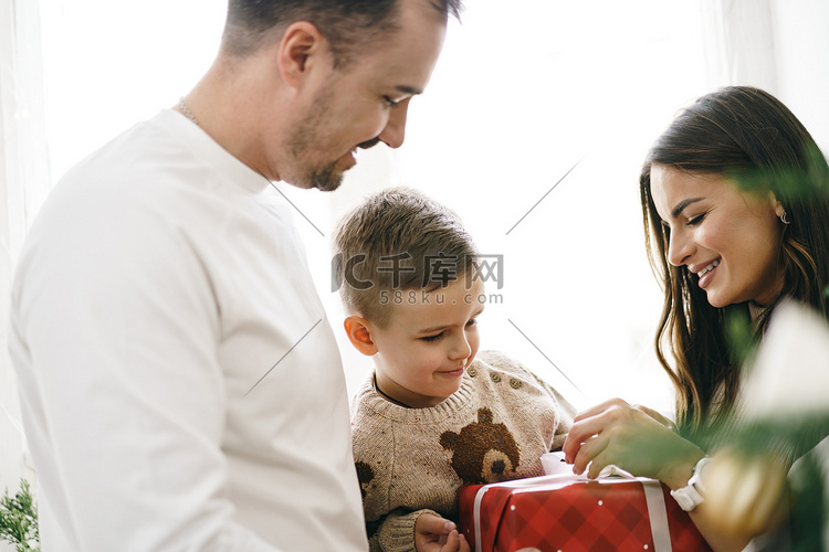 微笑的父母在家给儿子送圣诞礼物