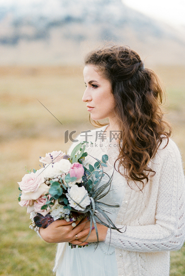 新娘带着一束鲜花在山谷中。