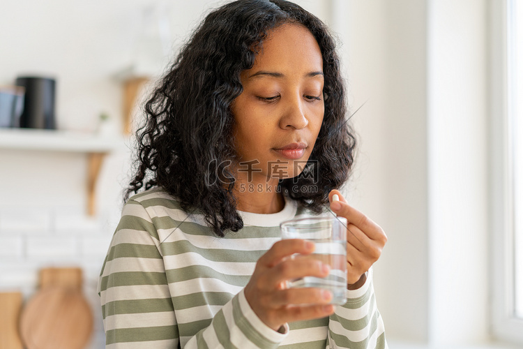 非裔美国女性用水冲洗药丸。健康