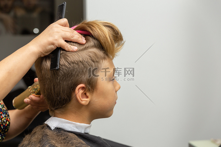 漂亮的欧洲男孩在理发店做发型。
