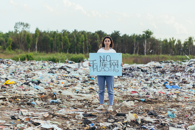 女志愿者在垃圾填埋场举着无塑料