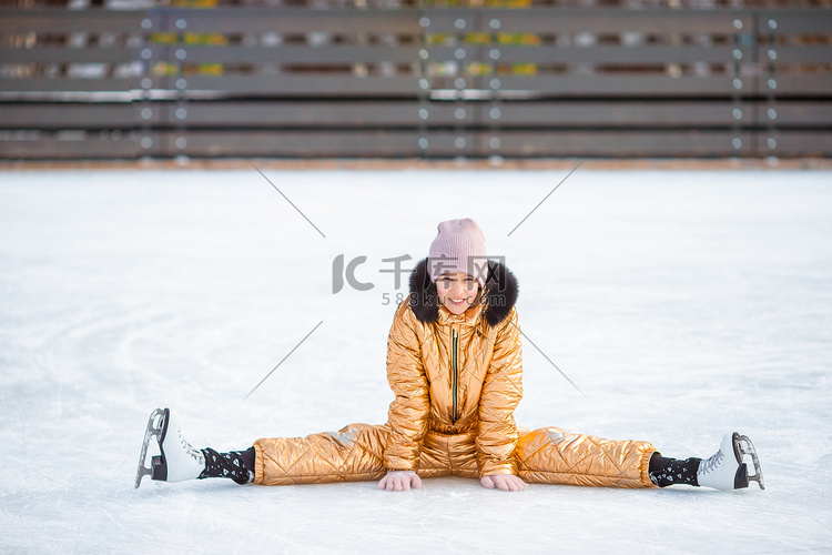 跌倒后坐在冰上溜冰鞋的可爱小女