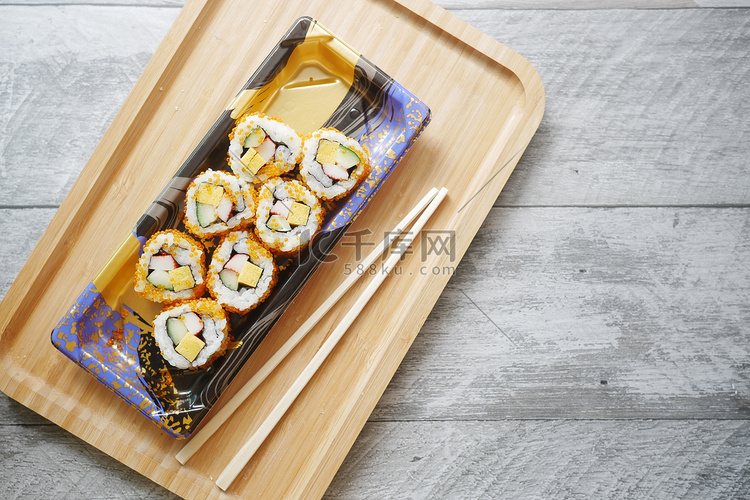 筷子、寿司卷，桌上放着鲑鱼、虾