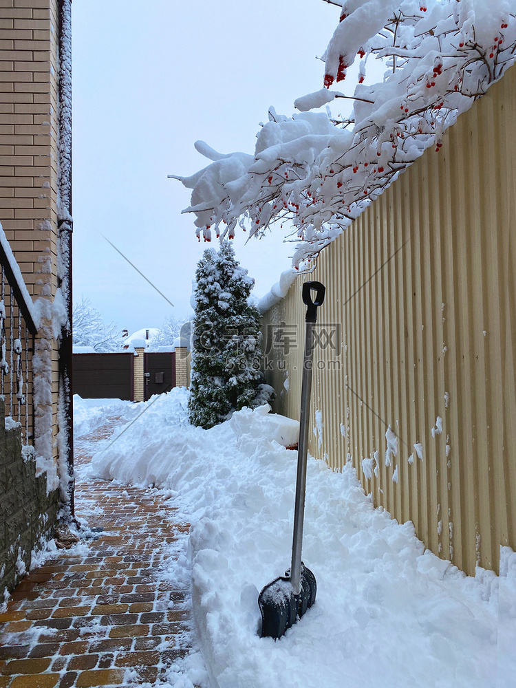 从房子院子里的人行道上铲雪：雪