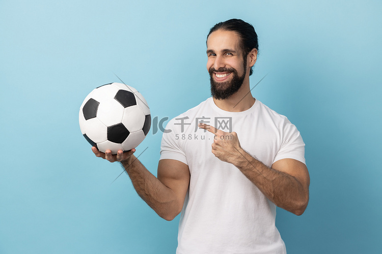 男人指着手中的足球，带着露齿的