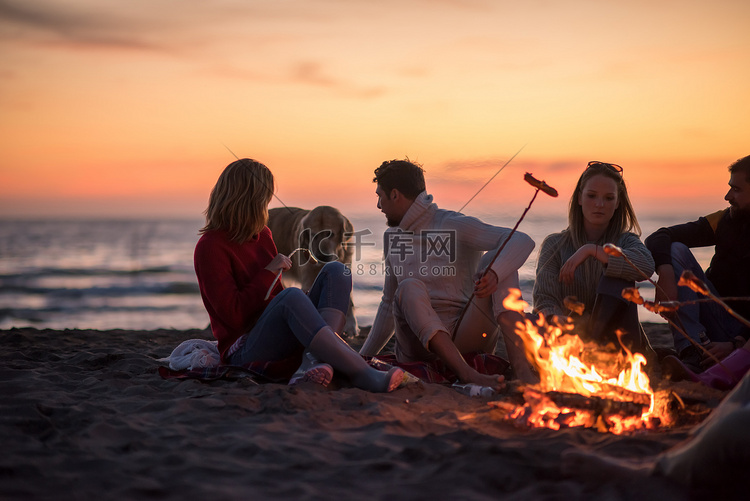 一群年轻的朋友坐在海滩的火边